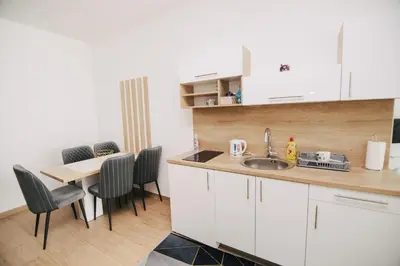 a kitchen with a sink and a table with chairs at KS Apartments in Visoko