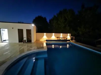 a swimming pool at night in front of a house at Villa AS in Bihać