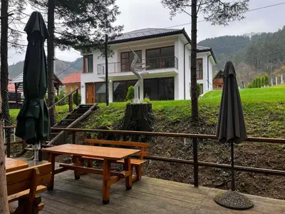 a house with a picnic table and two umbrellas at Villa Bella Una - Prizemlje in Cazin