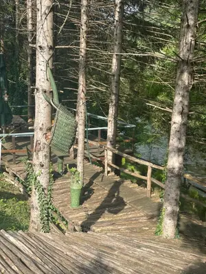 a green bench sitting on a wooden deck with trees at Villa Bella Una - Prizemlje in Cazin