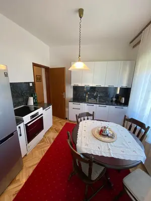 a kitchen with a table with a red rug at Apartment Alma in Bihać