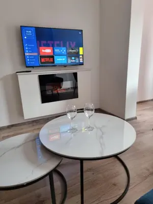 two wine glasses on a white table in front of a tv at Apartman Rita in Fojnica