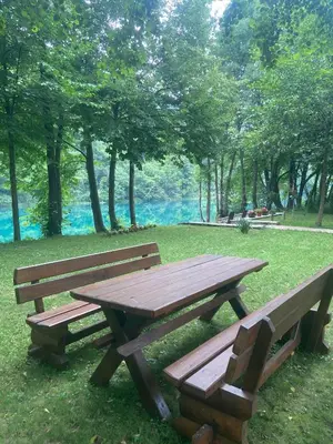 two wooden benches and a picnic table in a park at Holiday Home UnaPark in Krakovo