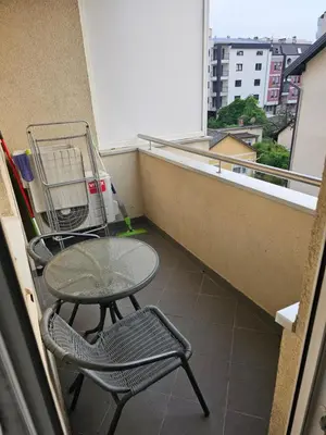 a table and a chair on a balcony with a window at Apartman City One in Banja Luka