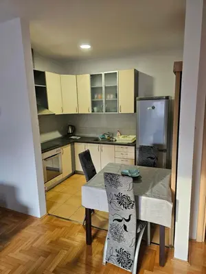 a kitchen with a table with chairs and a refrigerator at Apartman City One in Banja Luka