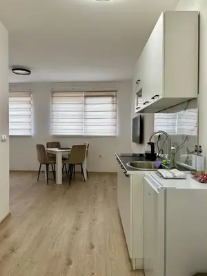 a kitchen with white cabinets and a table with chairs at Jelena in Jajce