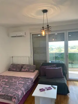 a bedroom with two beds and a table and a window at Oaza 3 in Doboj