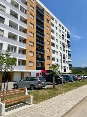 a parking lot with cars parked in front of a tall building at Oaza 3 in Doboj