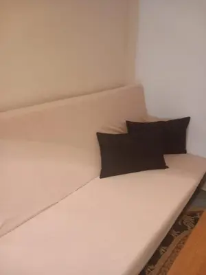 a white bed with two black pillows on it at Ema's apartments in Bihać