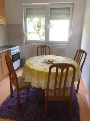 a kitchen with a table and chairs and a table and a window at Ema's apartments in Bihać