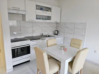a white kitchen with a white table and chairs at Apartman Sunce in Bosanska Gradiška
