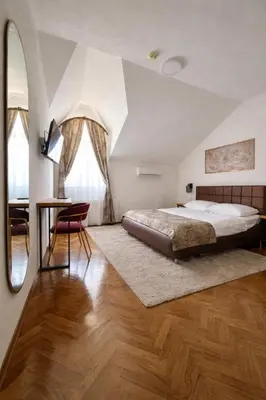 a bedroom with a bed and a table and a mirror at Motel Marić in Žepče