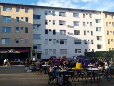 a group of people sitting at tables in front of a building at WUGE Bihac in Bihać