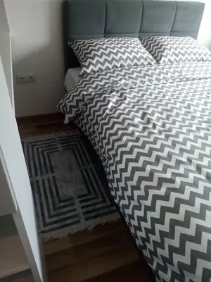 a bed with a black and white comforter and a rug at WUGE Bihac in Bihać