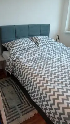 a bed with a black and white comforter on it at WUGE Bihac in Bihać