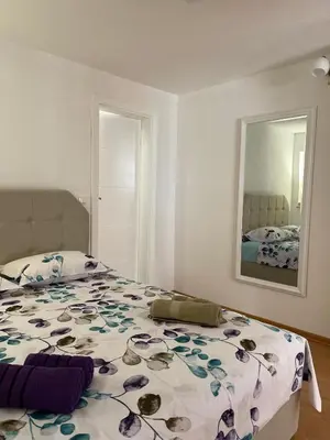 a bedroom with a bed with a floral bedspread and a mirror at Studio apartman Ana in Livno