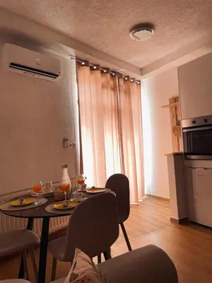a living room with a table and chairs and a kitchen at Studio apartman Ana in Livno
