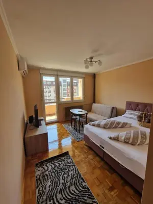 a bedroom with a bed and a couch and a table at Cozy in Zenica