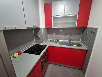 a small kitchen with red cabinets and a sink at Cozy in Zenica