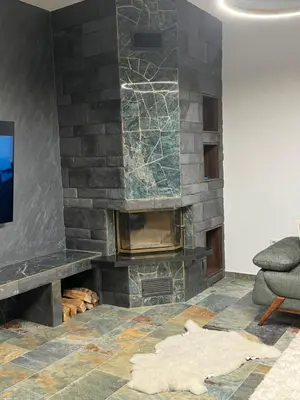 a living room with a stone fireplace and a chair at Cupcake Apartments in Šišava
