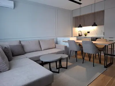 a living room with a couch and tables and a kitchen at Sparkle Home in Banja Luka