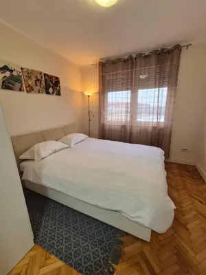 a bedroom with a bed with white sheets and a window at Apartman Srbac in Srbac