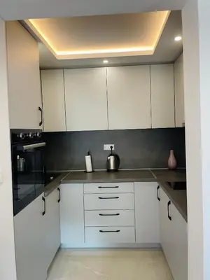 a white kitchen with white cabinets and black appliances at Hacienda DM in Visoko