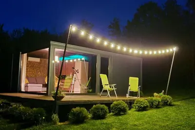 a tiny house with a deck with two chairs and lights at Kućica za odmor Srbac in Srbac