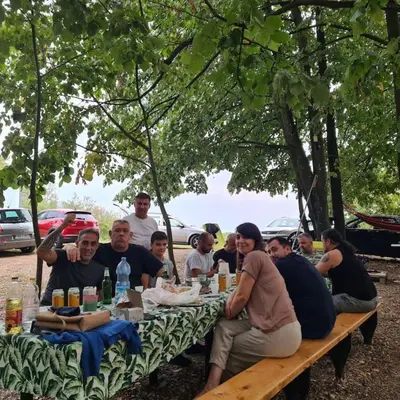 a group of people sitting at a picnic table at Kućica za odmor Srbac in Srbac