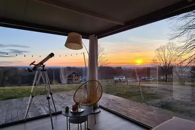 a view of a sunset through a window with a telescope at Kućica za odmor Srbac in Srbac