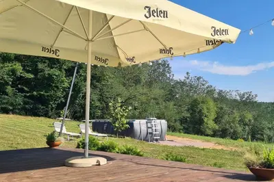 aige umbrella sitting on a patio next to a field at Kućica za odmor Srbac in Srbac