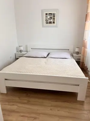 a white bed in a white bedroom with a white wall at Apartman Aldijana in Ripač