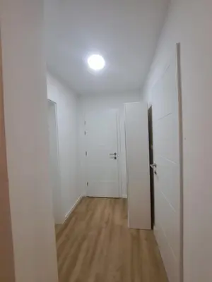 an empty room with two doors and a wooden floor at Apartman Aldijana in Ripač