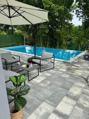 a patio with two chairs and an umbrella next to a pool at Villa Sofia in Bihać