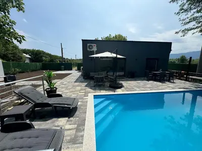 a swimming pool with chairs and a table and an umbrella at Villa Sofia in Bihać