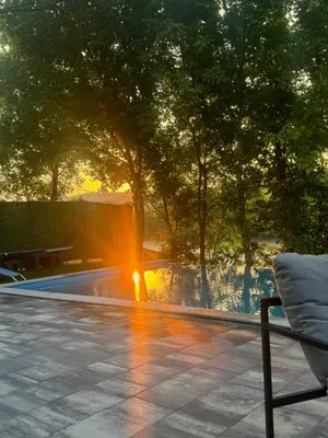 a swimming pool with a fountain with the sun setting at Villa Sofia in Bihać