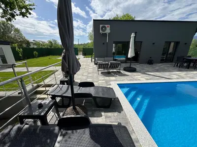 a patio with an umbrella and a swimming pool at Villa Sofia in Bihać