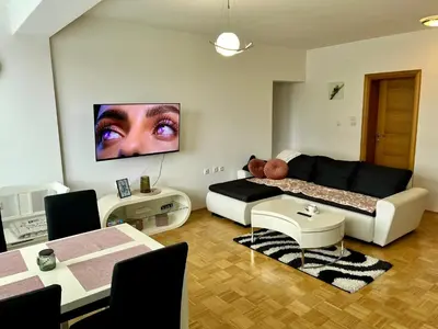 a living room with a couch and a tv on the wall at City Apartment Lukavac in Lukavac
