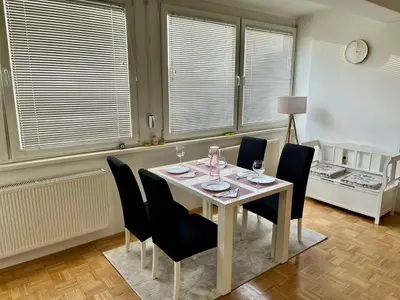 a dining room with a table and chairs and windows at City Apartment Lukavac in Lukavac
