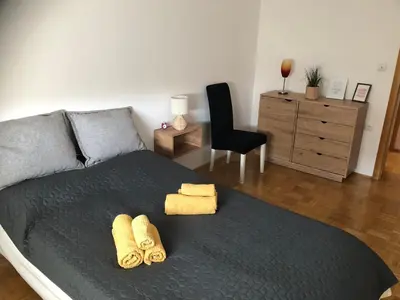 a bedroom with a bed with two towels and a chair at City Apartment Lukavac in Lukavac