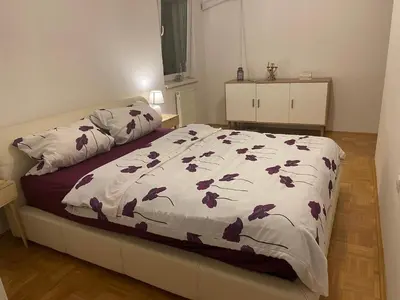 a bedroom with a bed with purple flowers on it at City Apartment Lukavac in Lukavac