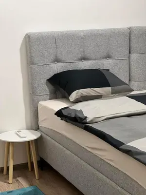 a bed with black and white pillows and a table at Apartman Zen Fojnica in Fojnica