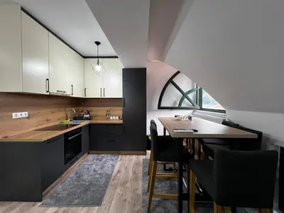 a kitchen with black and white cabinets and a table at Apartman Zen Fojnica in Fojnica