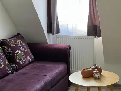 a purple couch in a living room with a table at Apartman Zen Fojnica in Fojnica