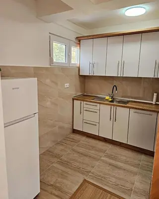 a kitchen with white cabinets and a white refrigerator at Stan TeslićTrg in Teslić