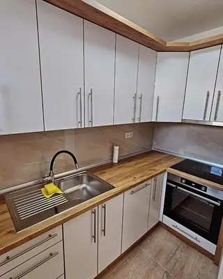 a kitchen with white cabinets and a sink at Stan TeslićTrg in Teslić