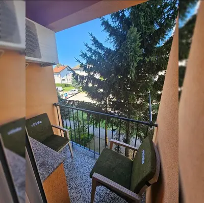 a balcony with two chairs and a tree at Stan TeslićTrg in Teslić