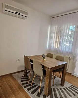 a dining room with a wooden table and chairs at Stan TeslićTrg in Teslić