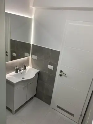 a white bathroom with a sink and a shower at Luxury Pyramid Apartment Visoko in Visoko