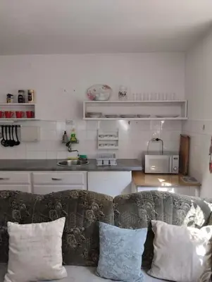 a living room with a couch with pillows and a kitchen at Apartman Turizam Plus in Travnik